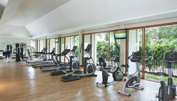 Santiburi Koh Samui's sports center: Treadmills, ellipticals, and stationary bikes face lush greenery. Fitness and wellness for gay travelers.